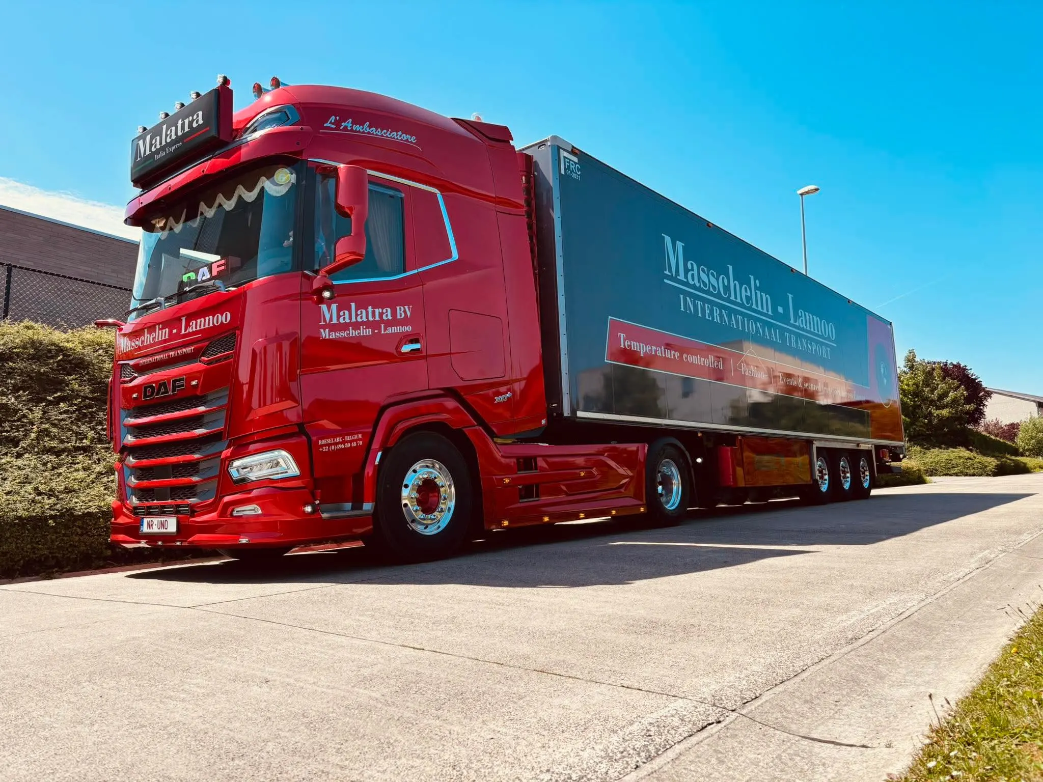 Rode Malatra DAF-trekker met koelwagentrailer, driekwart vooraanzicht tegen een strakblauwe hemel