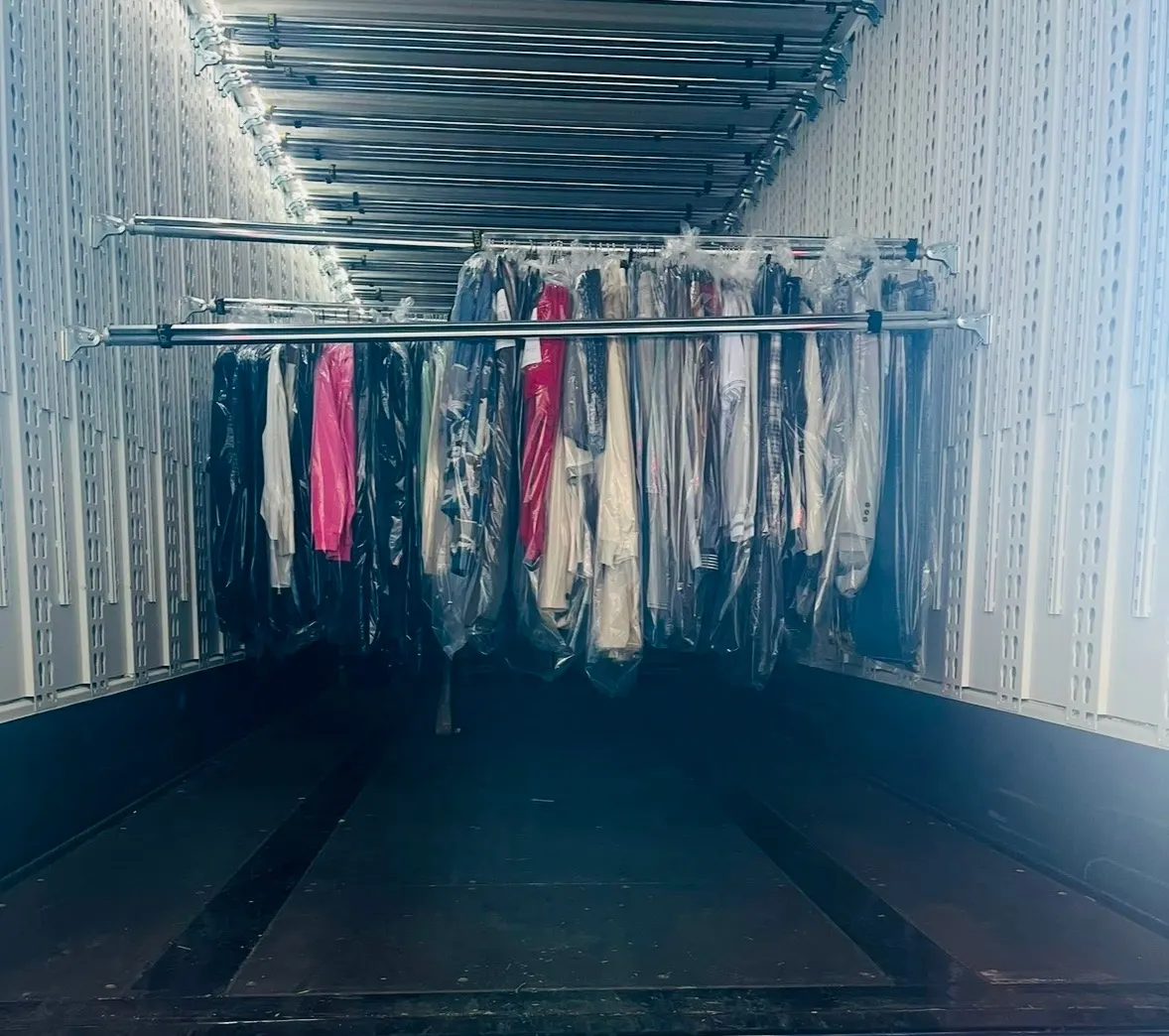 Kledingrekken met verpakte kledingstukken hangend in een Malatra-trailer